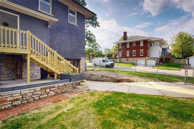 view of yard with stairs, a garage, and driveway