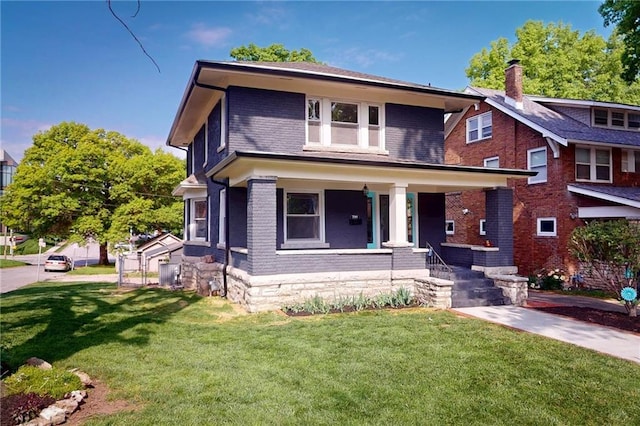 american foursquare style home featuring brick siding, a porch, and a front lawn