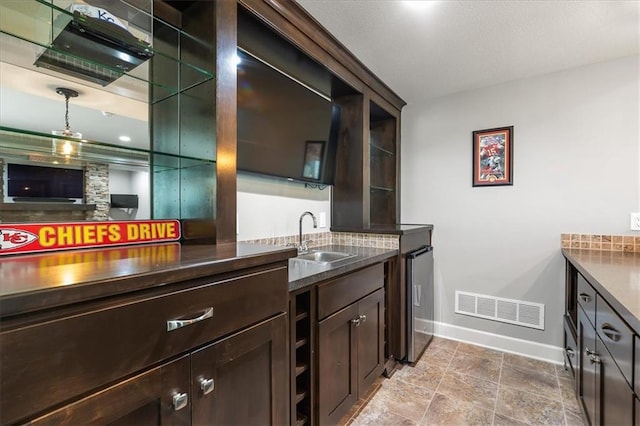 17817 Grandview St, Overland Park, KS 66013 - kitchen featuring a sink, baseboards, dark brown cabinetry, dark stone counters, and decorative backsplash
