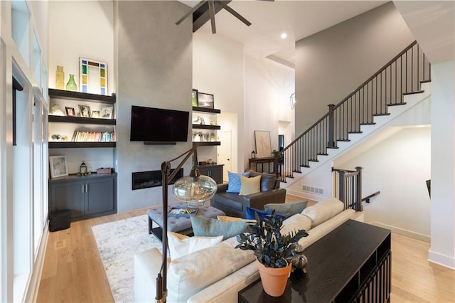 17328 Richards St, Overland Park, KS 66221 - living area with a high ceiling, a fireplace, a ceiling fan, wood finished floors, and stairs