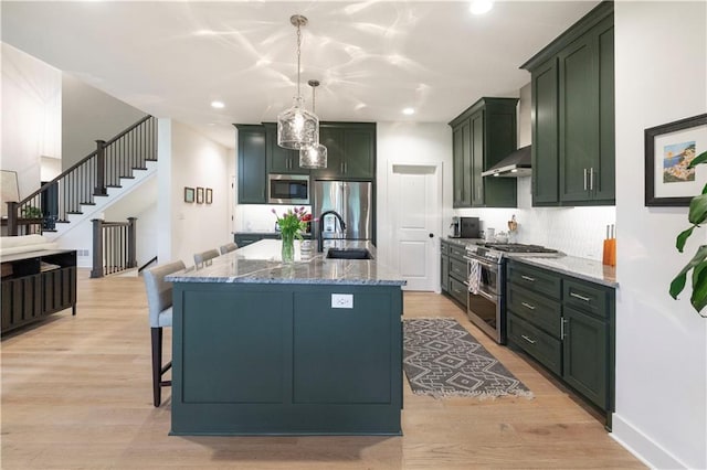 17328 Richards St, Overland Park, KS 66221 - kitchen featuring appliances with stainless steel finishes, green cabinetry, light stone countertops, wall chimney range hood, and a sink