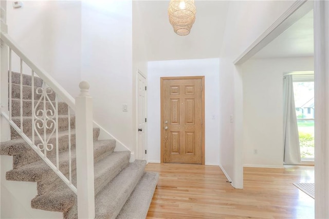 foyer entrance with stairs, light wood-style floors, and baseboards
