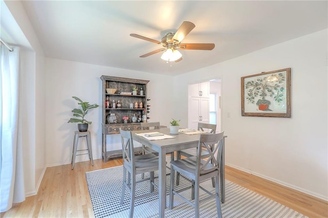 dining room with ceiling fan, light wood-style flooring, and baseboards