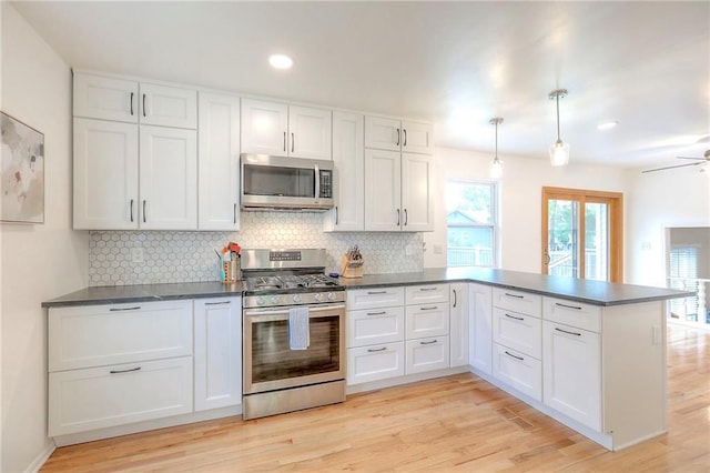kitchen with stainless steel appliances, a peninsula, dark countertops, decorative backsplash, and recessed lighting