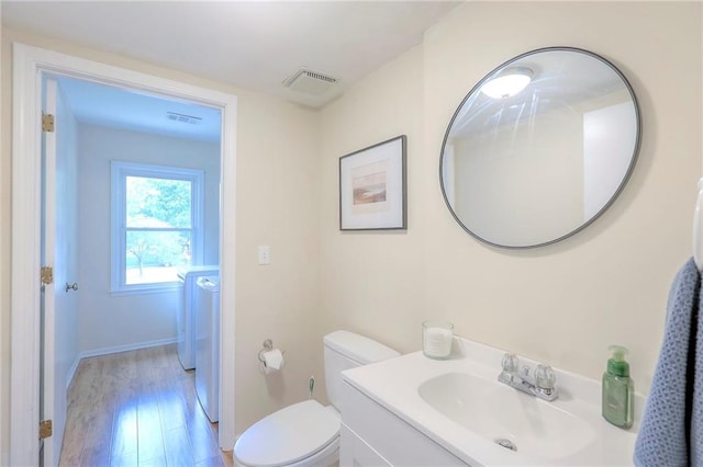 bathroom with wood finished floors, toilet, vanity, independent washer and dryer, and baseboards
