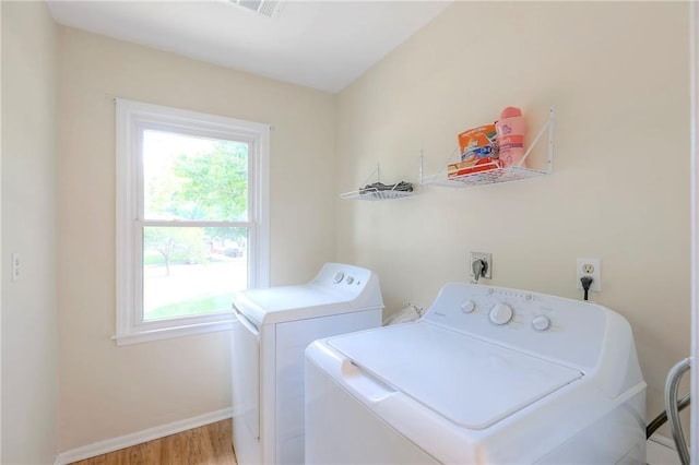 clothes washing area with plenty of natural light, baseboards, separate washer and dryer, and wood finished floors