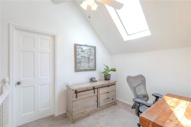 home office featuring vaulted ceiling, light colored carpet, a skylight, a ceiling fan, and baseboards