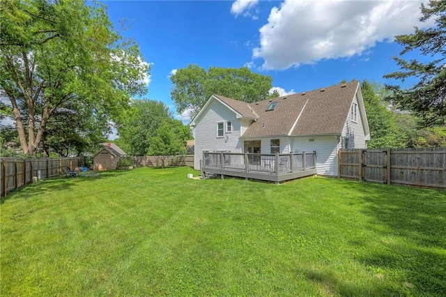 rear view of property featuring a deck, a storage shed, a shingled roof, and an outdoor structure