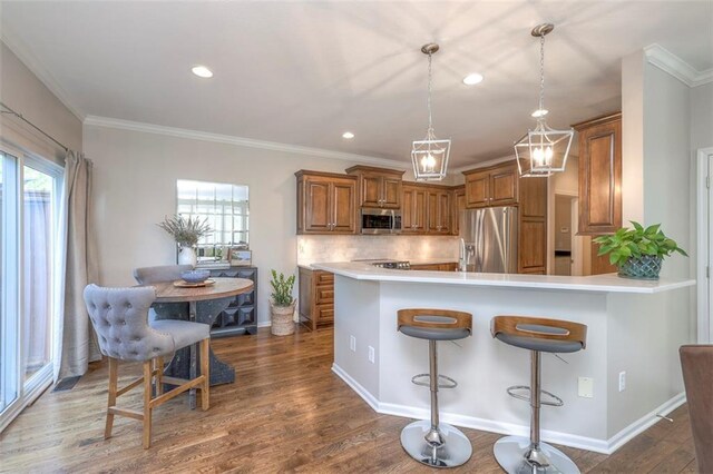 16141 Linden St, Stilwell, KS 66085 - kitchen featuring appliances with stainless steel finishes, brown cabinets, decorative backsplash, dark wood-style floors, and a breakfast bar area