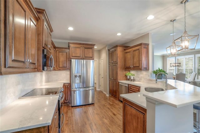 16141 Linden St, Stilwell, KS 66085 - kitchen featuring stainless steel appliances, a sink, a peninsula, recessed lighting, and brown cabinets