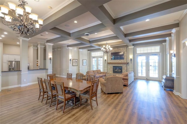 16141 Linden St, Stilwell, KS 66085 - dining space with a chandelier, a stone fireplace, beam ceiling, crown molding, and light wood-type flooring