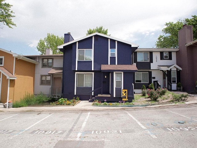 10921 Mckinley Dr, Kansas City, MO 64134 - view of property with a chimney, uncovered parking, and stucco siding