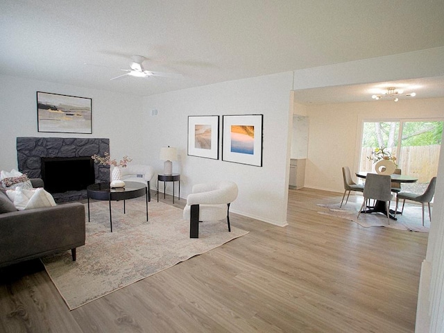 10921 Mckinley Dr, Kansas City, MO 64134 - living room featuring light wood-style flooring, a ceiling fan, a fireplace, and baseboards