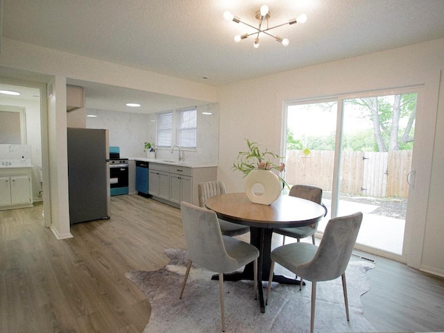 10921 Mckinley Dr, Kansas City, MO 64134 - dining room with light wood-type flooring, a chandelier, and plenty of natural light