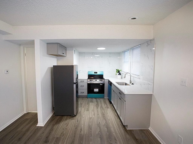 10921 Mckinley Dr, Kansas City, MO 64134 - kitchen with stainless steel appliances, a sink, gray cabinetry, wood finished floors, and a textured ceiling