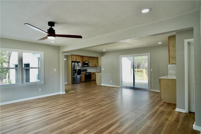 10514 E 35th St S, Independence, MO 64052 - unfurnished living room featuring wood finished floors, ceiling fan, a textured ceiling, baseboards, and recessed lighting