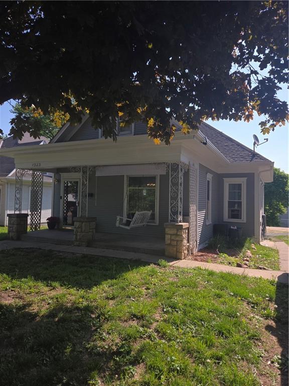 bungalow-style home featuring covered porch and a front lawn