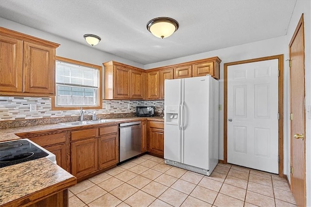 kitchen with white refrigerator with ice dispenser, a sink, stainless steel dishwasher, brown cabinets, and a textured ceiling