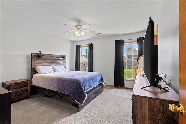 bedroom featuring light carpet, multiple windows, a ceiling fan, and baseboards