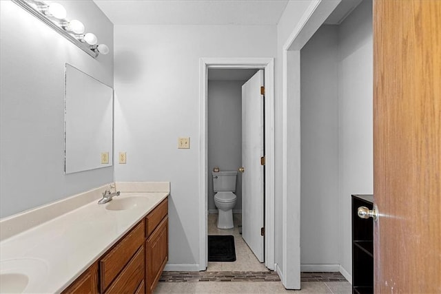 full bathroom featuring toilet, double vanity, baseboards, and tile patterned floors