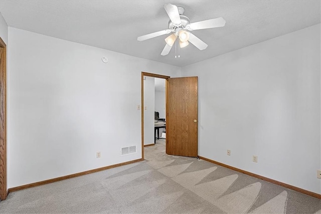 spare room with light carpet, baseboards, and ceiling fan