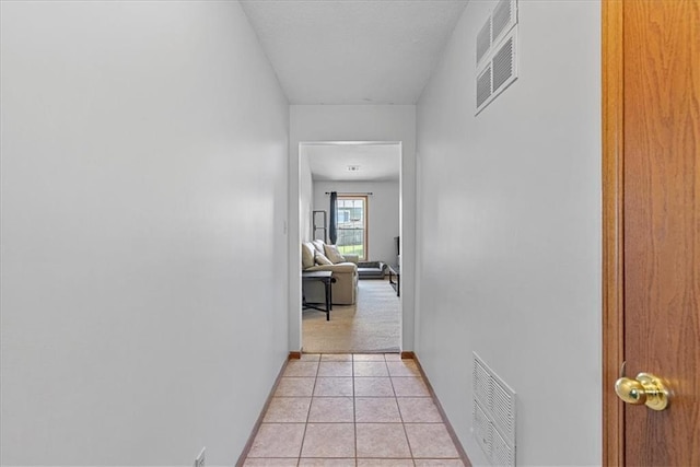 hallway featuring baseboards and light tile patterned flooring