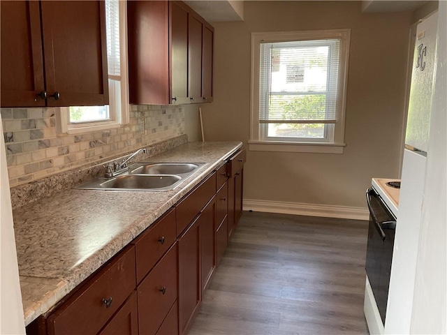 3624 Mersington Ave, Kansas City, MO 64128 - kitchen featuring baseboards, white electric range, a sink, decorative backsplash, and light wood-type flooring
