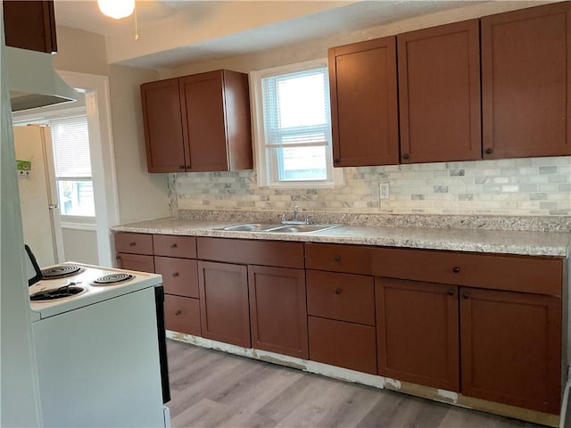 3624 Mersington Ave, Kansas City, MO 64128 - kitchen featuring white appliances, a sink, tasteful backsplash, light wood-style floors, and healthy amount of natural light