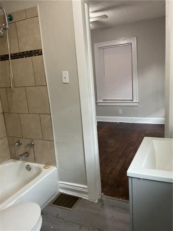 3624 Mersington Ave, Kansas City, MO 64128 - full bathroom with wood finished floors, toilet, shower / washtub combination, baseboards, and vanity