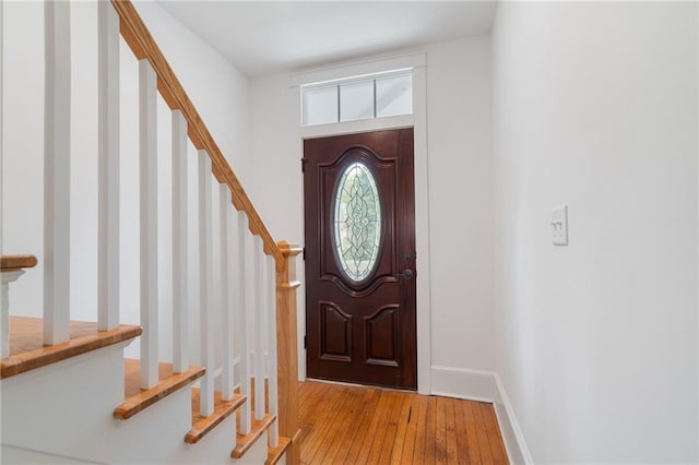 foyer featuring stairs, hardwood / wood-style flooring, and baseboards