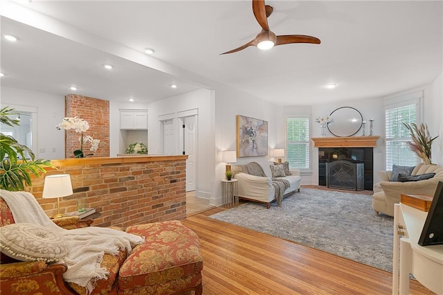 living room featuring a fireplace, light wood finished floors, ceiling fan, recessed lighting, and baseboards