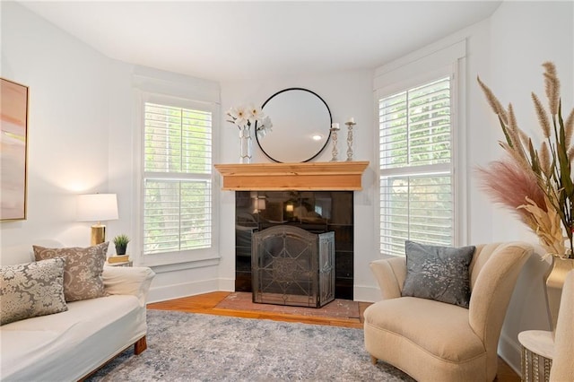 living area featuring wood finished floors, healthy amount of natural light, a tile fireplace, and baseboards