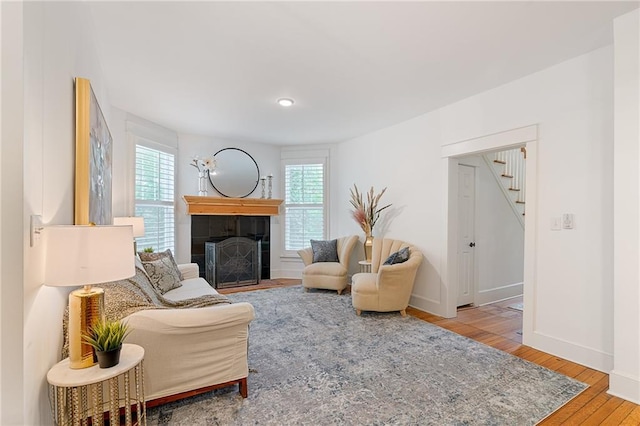 living room with stairs, wood finished floors, a tile fireplace, and baseboards