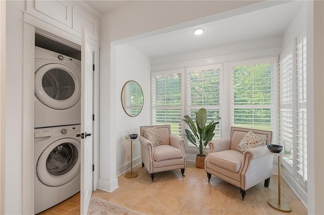 washroom featuring stacked washer / drying machine, healthy amount of natural light, and baseboards