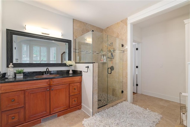 bathroom with a shower stall, vanity, baseboards, and tile patterned flooring