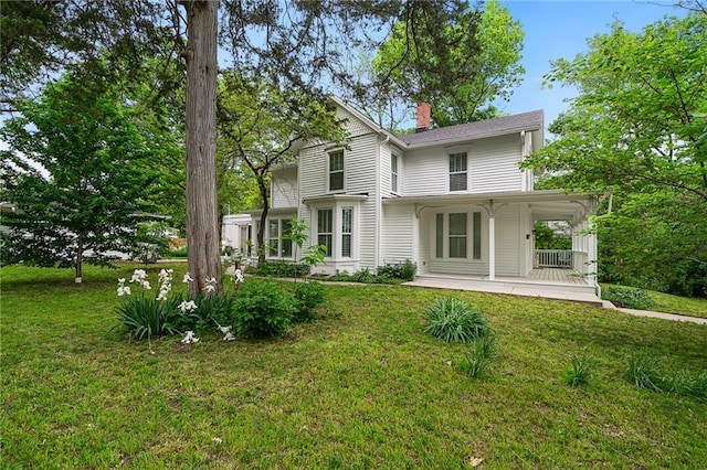 rear view of property with a yard, a chimney, and covered porch