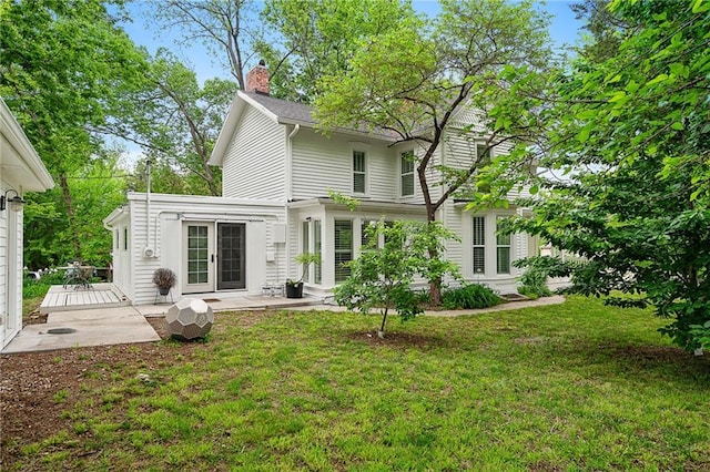 back of house featuring french doors, a lawn, a chimney, and a deck