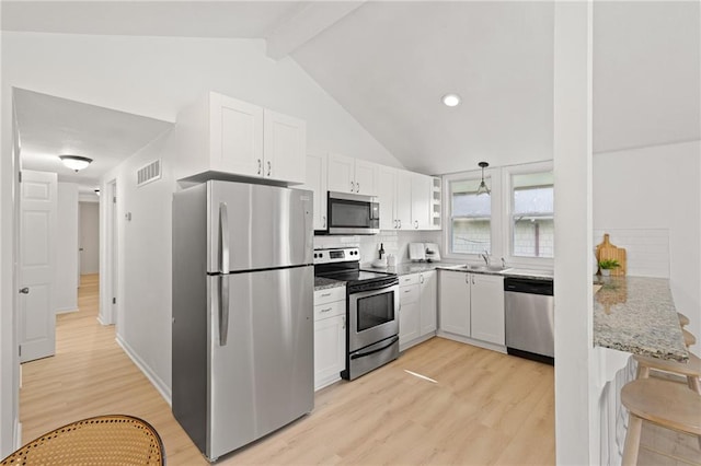 kitchen featuring stainless steel appliances, light wood-type flooring, white cabinets, light stone countertops, and tasteful backsplash