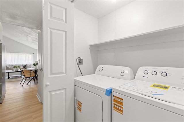 washroom with washer and dryer, light wood-style flooring, and a textured ceiling
