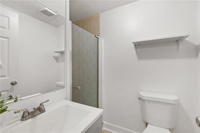 full bathroom featuring toilet, a stall shower, a textured ceiling, vanity, and baseboards