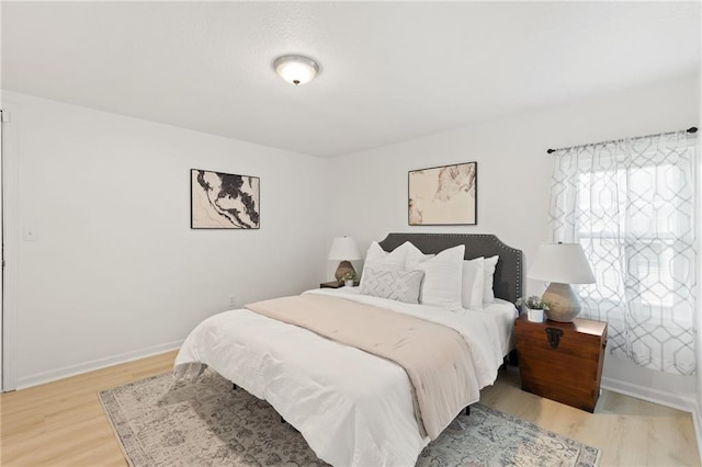 bedroom with light wood finished floors and baseboards