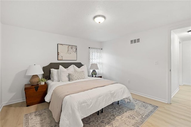 bedroom featuring light wood finished floors and baseboards
