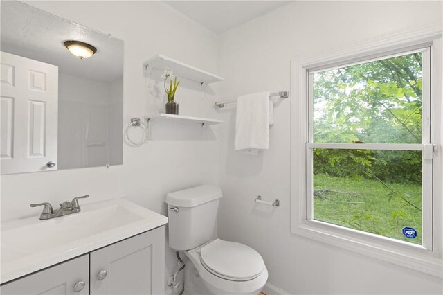 bathroom with toilet, vanity, and baseboards