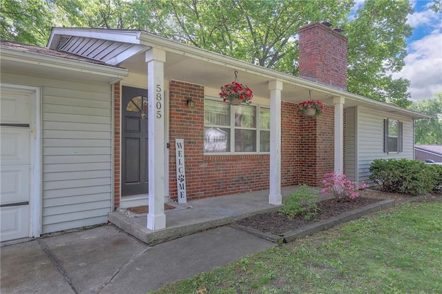 5805 N Belton Ave, Kansas City, MO 64151 - doorway to property with a porch, a chimney, brick siding, and a garage