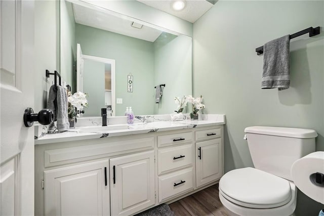 bathroom with toilet, wood finished floors, and vanity