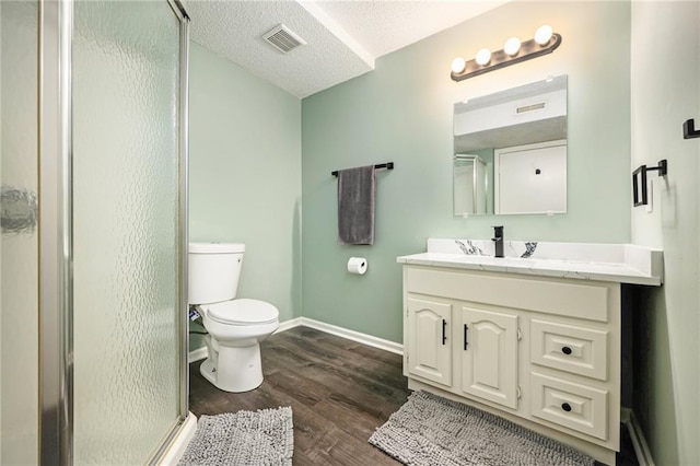 full bath with a shower stall, toilet, wood finished floors, vanity, and a textured ceiling