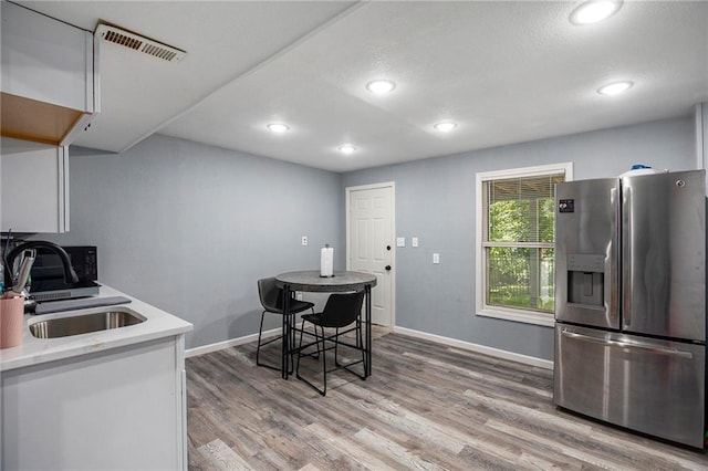 18213 Cliff Dr, Independence, MO 64055 - kitchen with stainless steel refrigerator with ice dispenser, a sink, light countertops, light wood finished floors, and baseboards