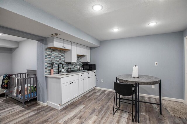 18213 Cliff Dr, Independence, MO 64055 - kitchen with a sink, white cabinetry, tasteful backsplash, light countertops, and wood finished floors