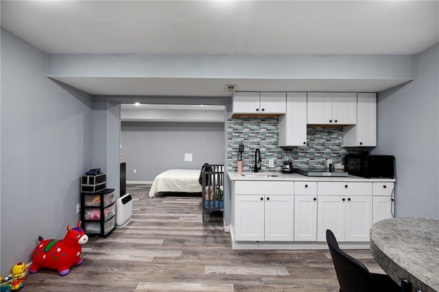 18213 Cliff Dr, Independence, MO 64055 - kitchen featuring a sink, black microwave, light wood-type flooring, and white cabinetry