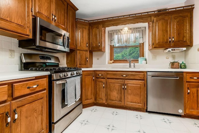 2820 S Victoria Ln, Blue Springs, MO 64015 - kitchen featuring appliances with stainless steel finishes, light countertops, brown cabinetry, and tasteful backsplash
